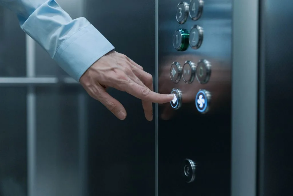 A hand pressing a button on an elevator panel